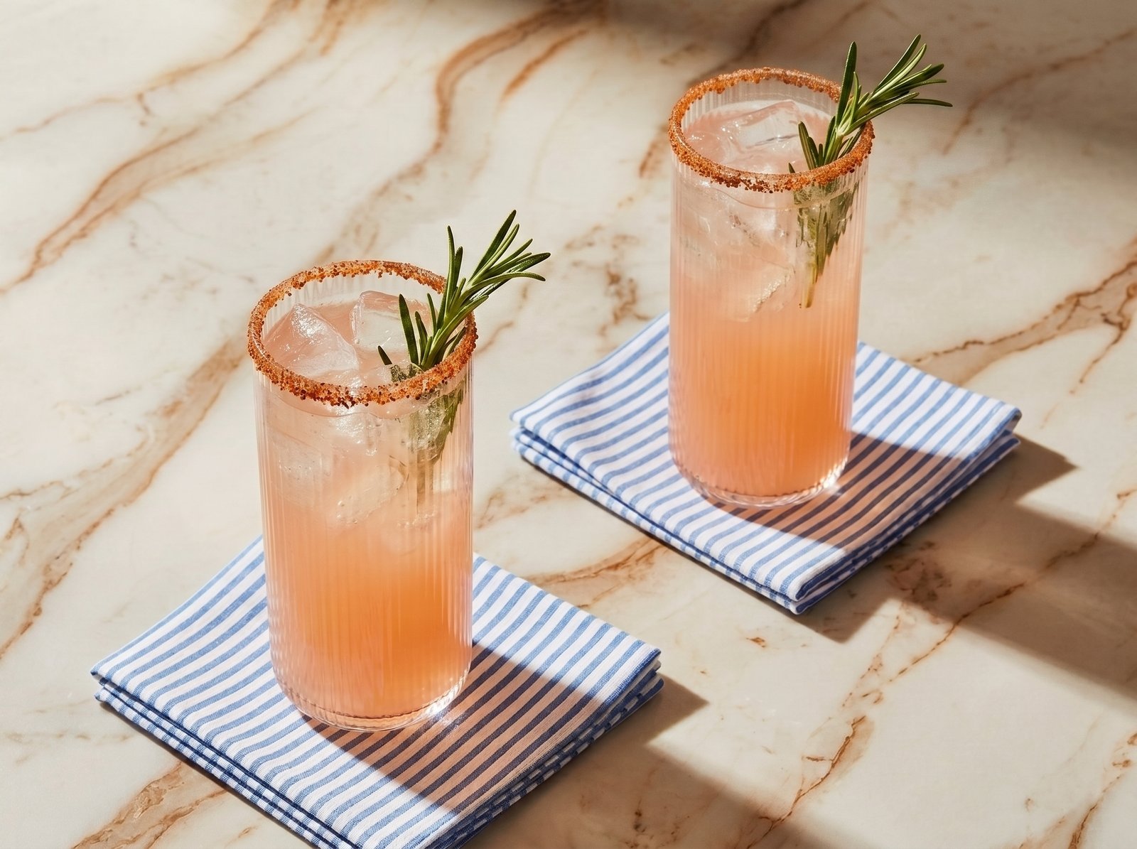 A finished rimmed cocktail on a beach at sunset